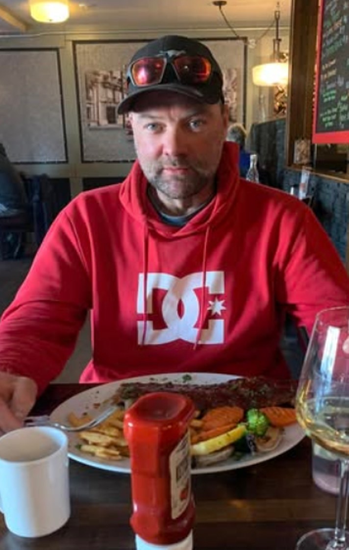 Marco Rivest in rotem Kapuzenpullover an einem Restauranttisch vor einem vollen Teller
